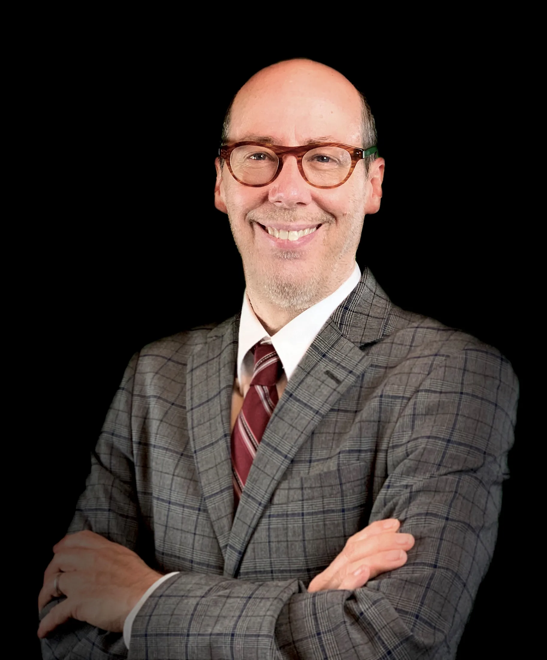 Portrait of Jack Bobo wearing a brown checkered suit and smiles at the camera.