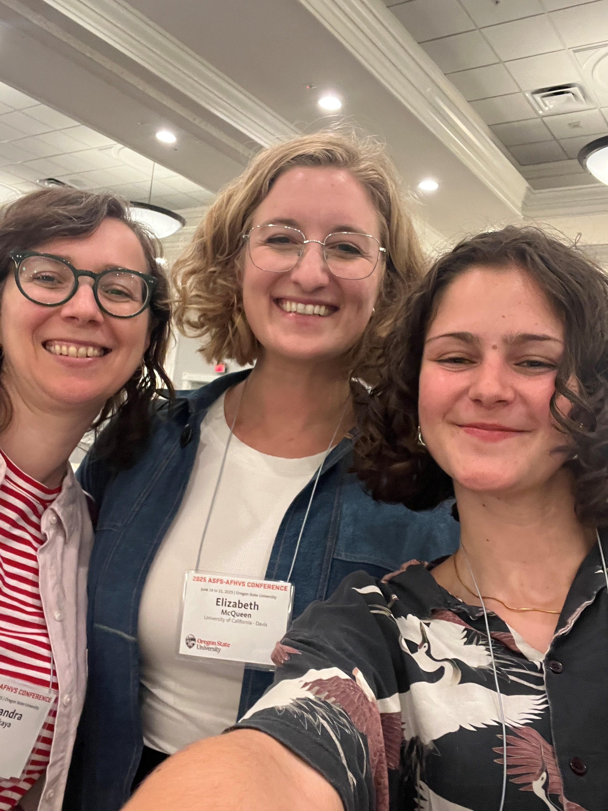 A selfie of Sarah Schecter and two other woman. Sarah has short curly hair and smiles at the camera.